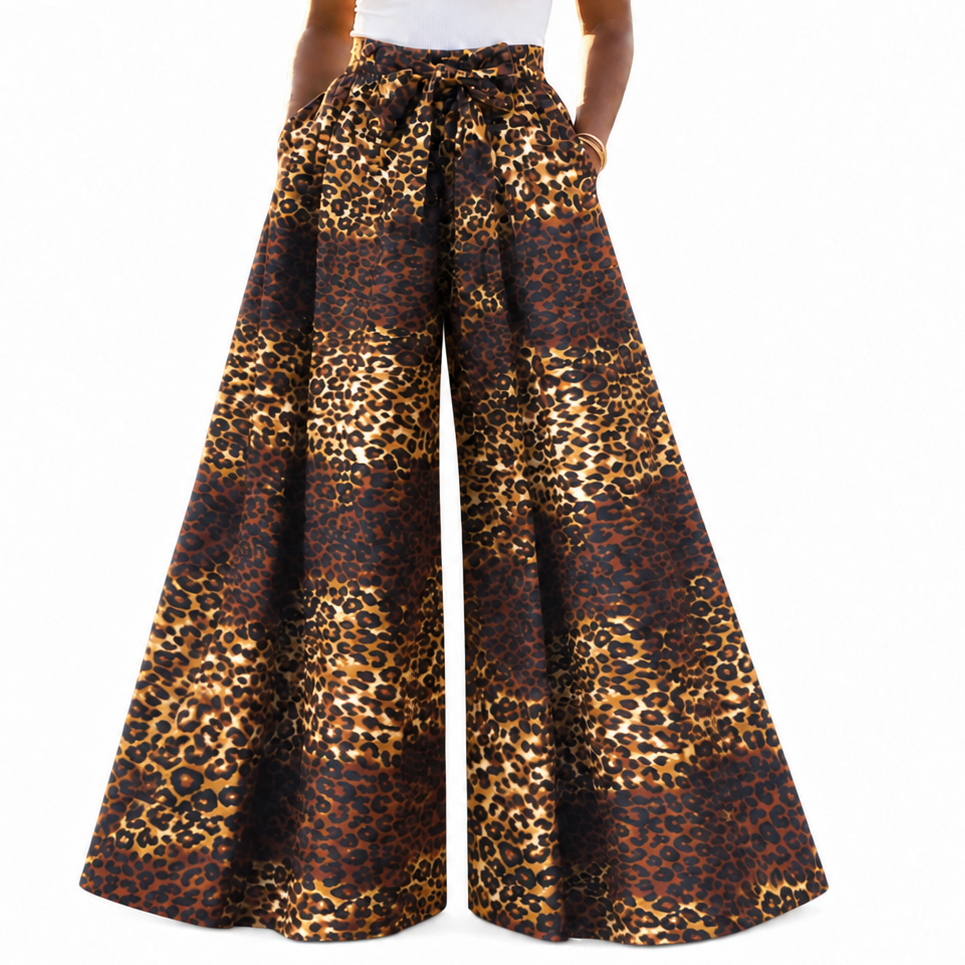 A model wearing high-waisted, wide-leg pants with a brown and gold leopard print pattern, paired with a white tank top, against a plain white background.