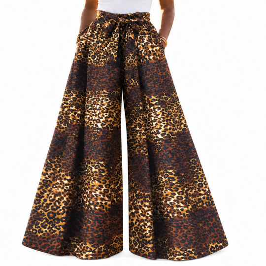 A model wearing high-waisted, wide-leg pants with a brown and gold leopard print pattern, paired with a white tank top, against a plain white background.