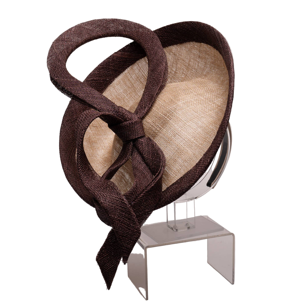 Brown and beige decorative hat on a stand against a plain background