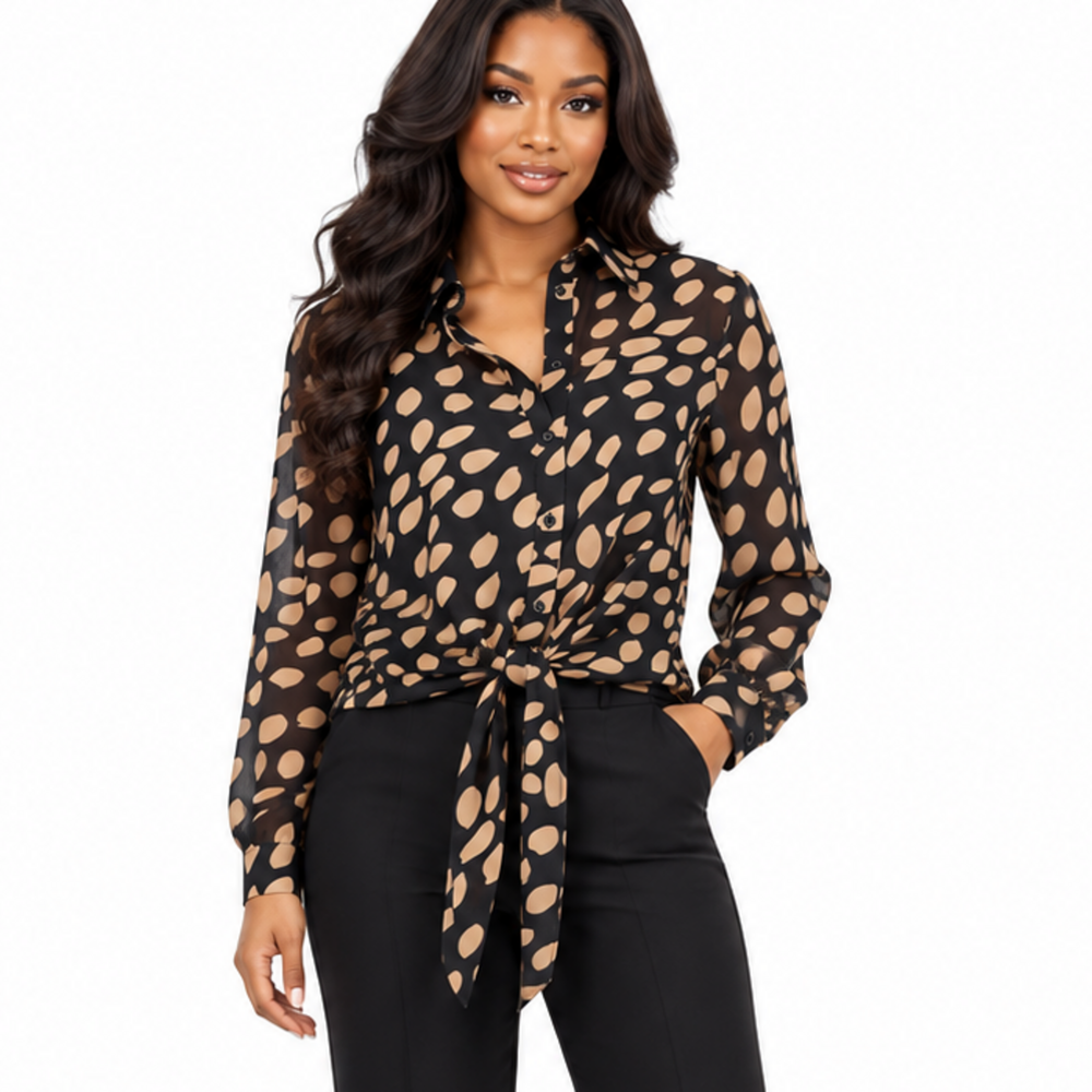 A woman modeling a black long-sleeve button-up blouse with a beige abstract spot pattern, tied at the waist, paired with black pants against a plain white background.