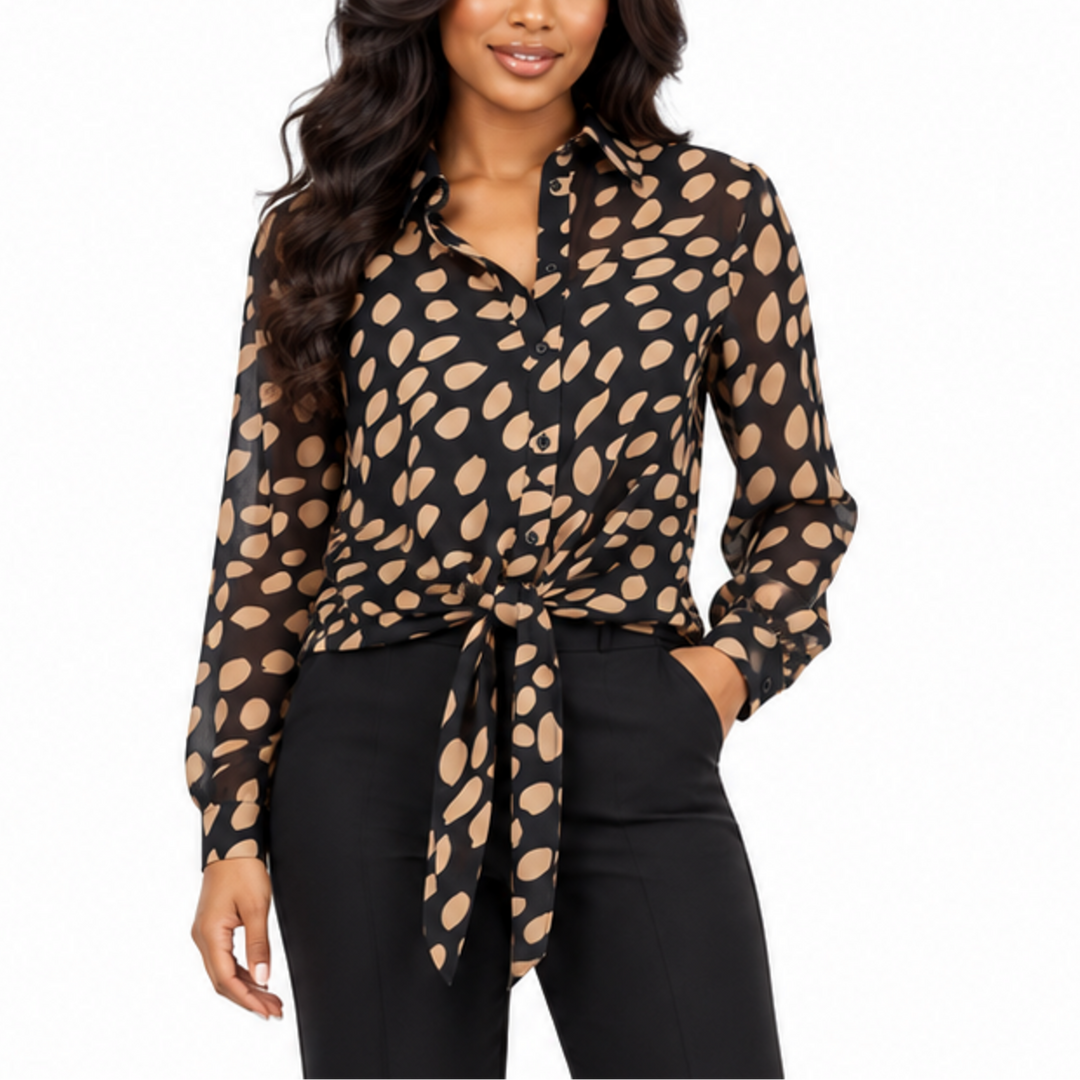 A woman modeling a black long-sleeve button-up blouse with a beige abstract spot pattern, tied at the waist, paired with black pants against a plain white background.
