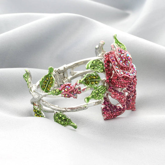 Decorative ring with pink rose and green leaves on white satin background