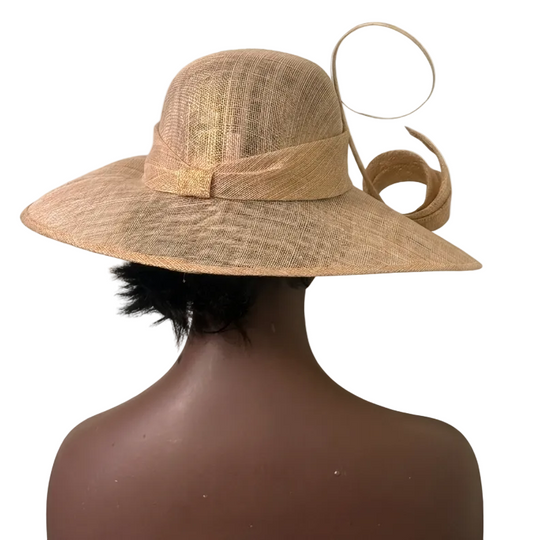Brown straw hat with decorative feather on a mannequin head against a beige background