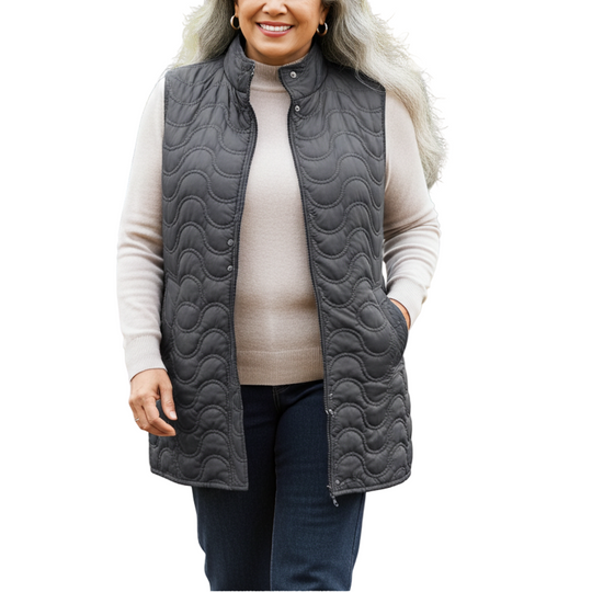 Woman wearing a gray quilted vest in a park with trees and grass.