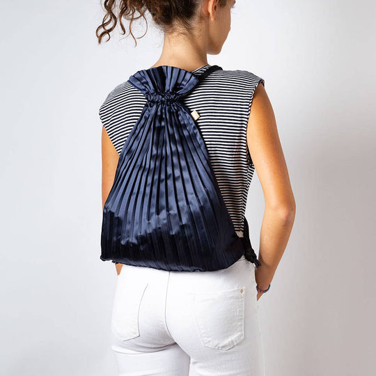 Write Sketch & - BLUE NAVY SATIN PLEATED BACKPACK
Navy blue color satin pleated backpack, fully open and extended size 44 x 45 cm. The backpack is made of permanently pleated silk-effect synthetic satin, with black loops and adjustable cords in high quality blue braid in contrast with the satin of the bag. The backpacks are designed to be used every day, they are very capacious and resistant as well as elegant and well finished. The opening is very simple and the closure is done by pulling the cords of the