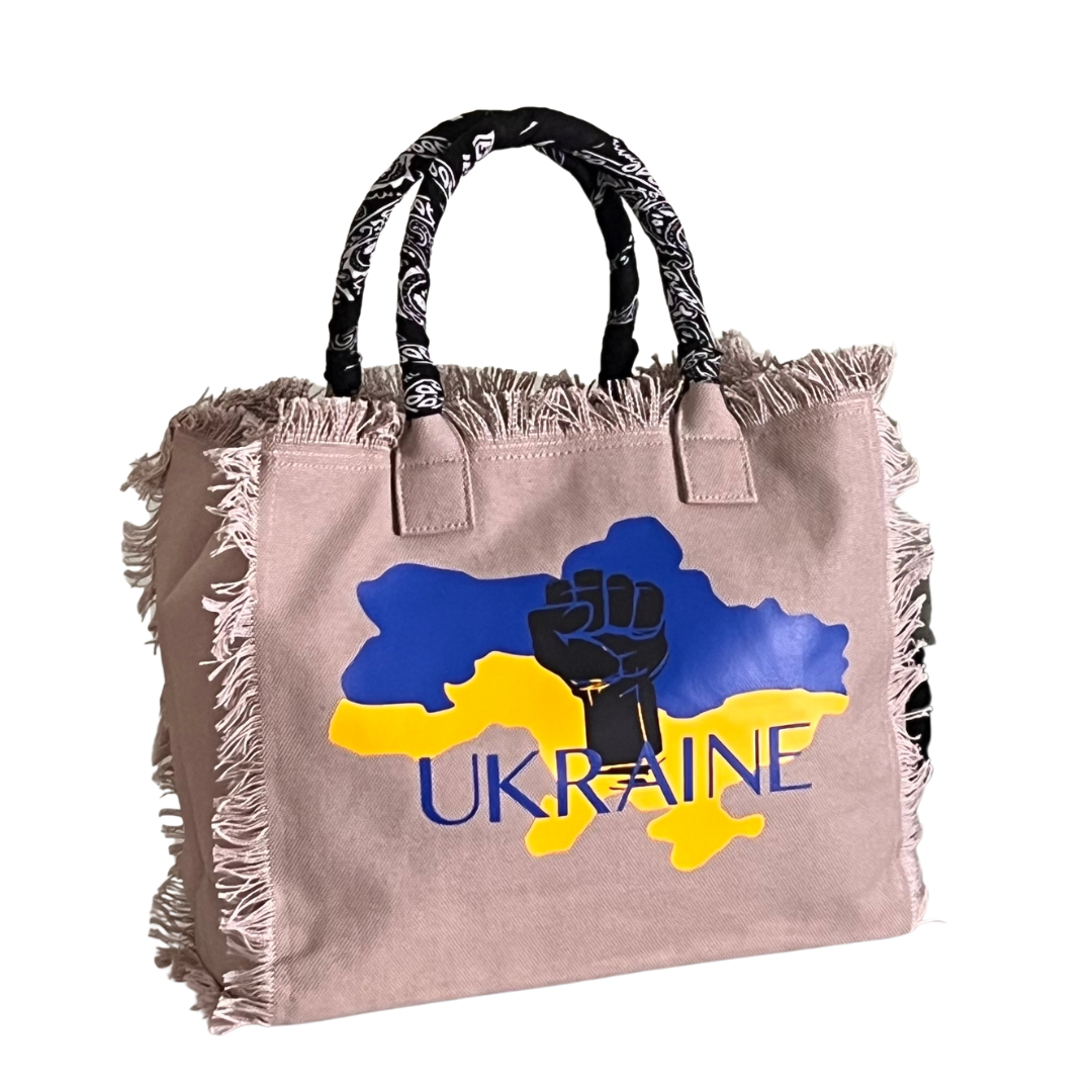 FUNDRAISER - Ukraine Shoulder Tote - Beige
This expressive tote was designed as part of the Sandi_J Strength & Unity Tote Collection. The unique design signifies standing in solidarity with our Ukrainian sisters and brothers. 50% of proceeds will be donated to SIFH Global (501c3) for the purchase and delivery of diesel generators to Ukraine Fully lined canvas tote with soft-support bottom and bandana covered handles. Inside bag has 1 convenient inside zippered pockets and 2 insert pockets. Bag handles are a